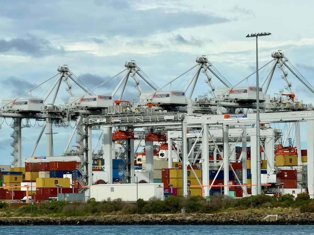 A bustling automated container terminal in Port Melbourne, showcasing cranes and shipping containers.