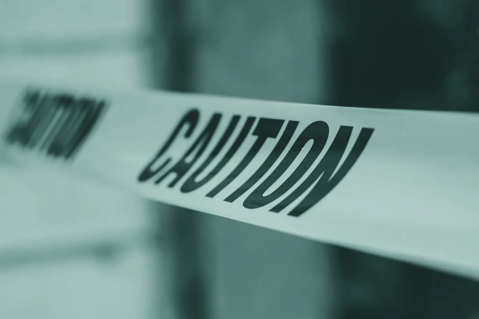 Close-up image of yellow caution tape with blurred background, emphasizing warning and safety.