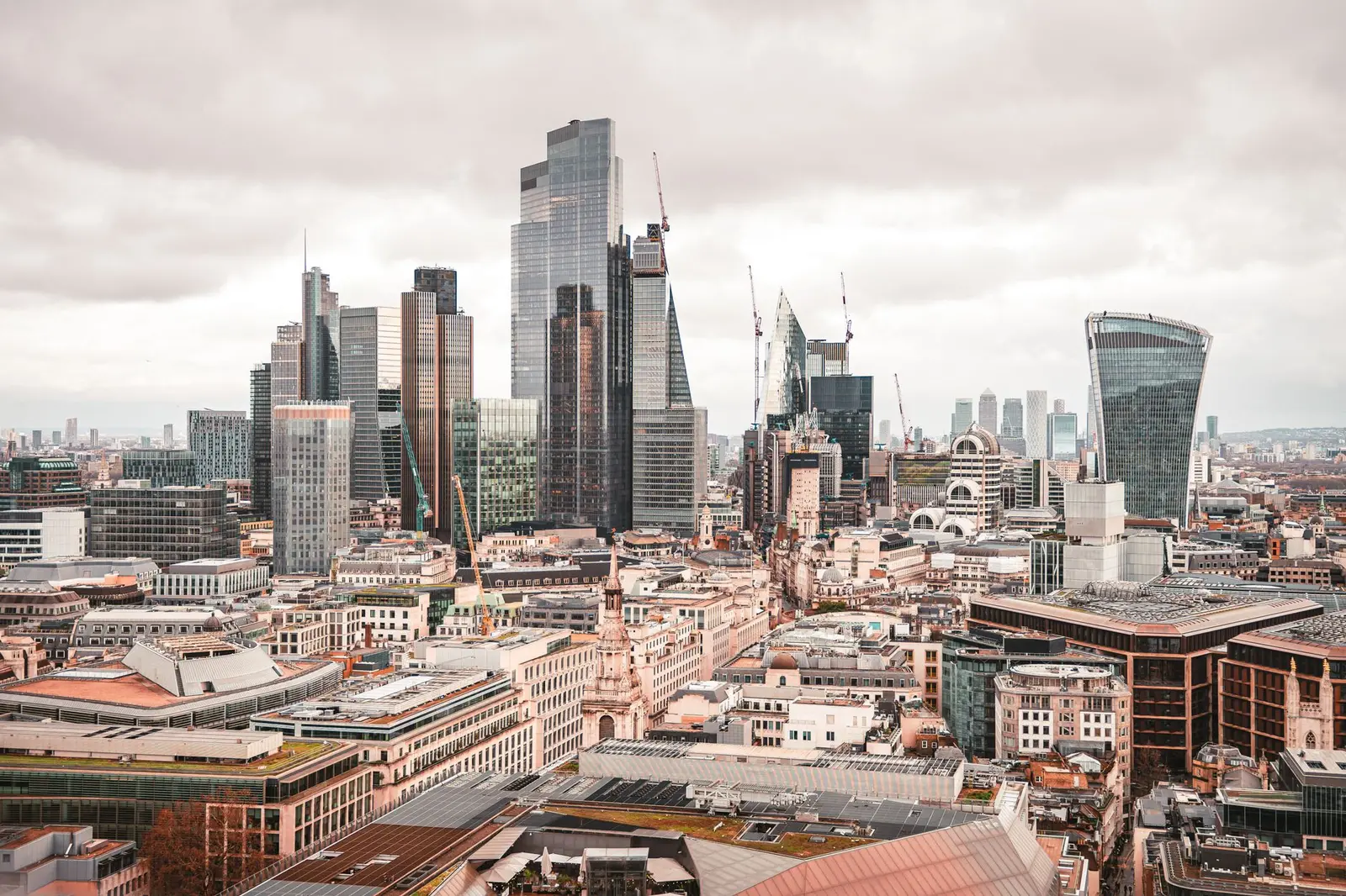 A stunning aerial view of London's modern skyscrapers under overcast skies, showcasing its architectural marvels.