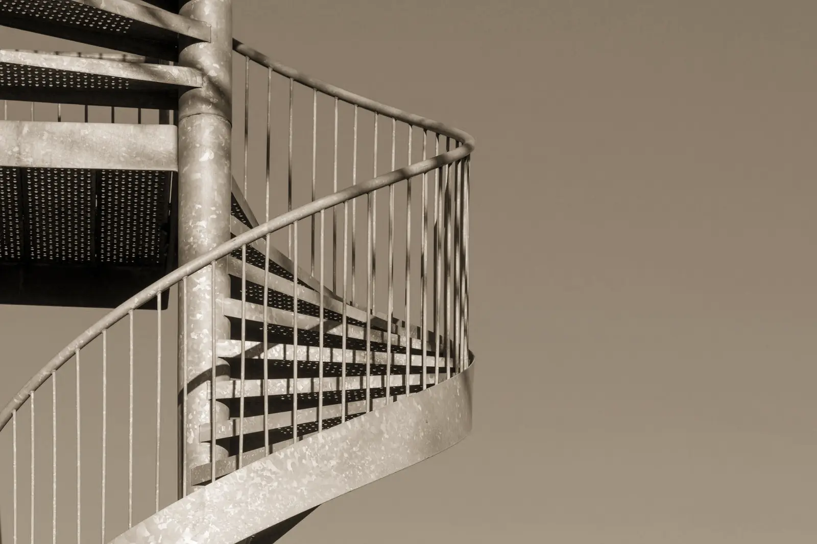 A metal spiral staircase set against a vivid blue sky, showcasing architectural design and open space.