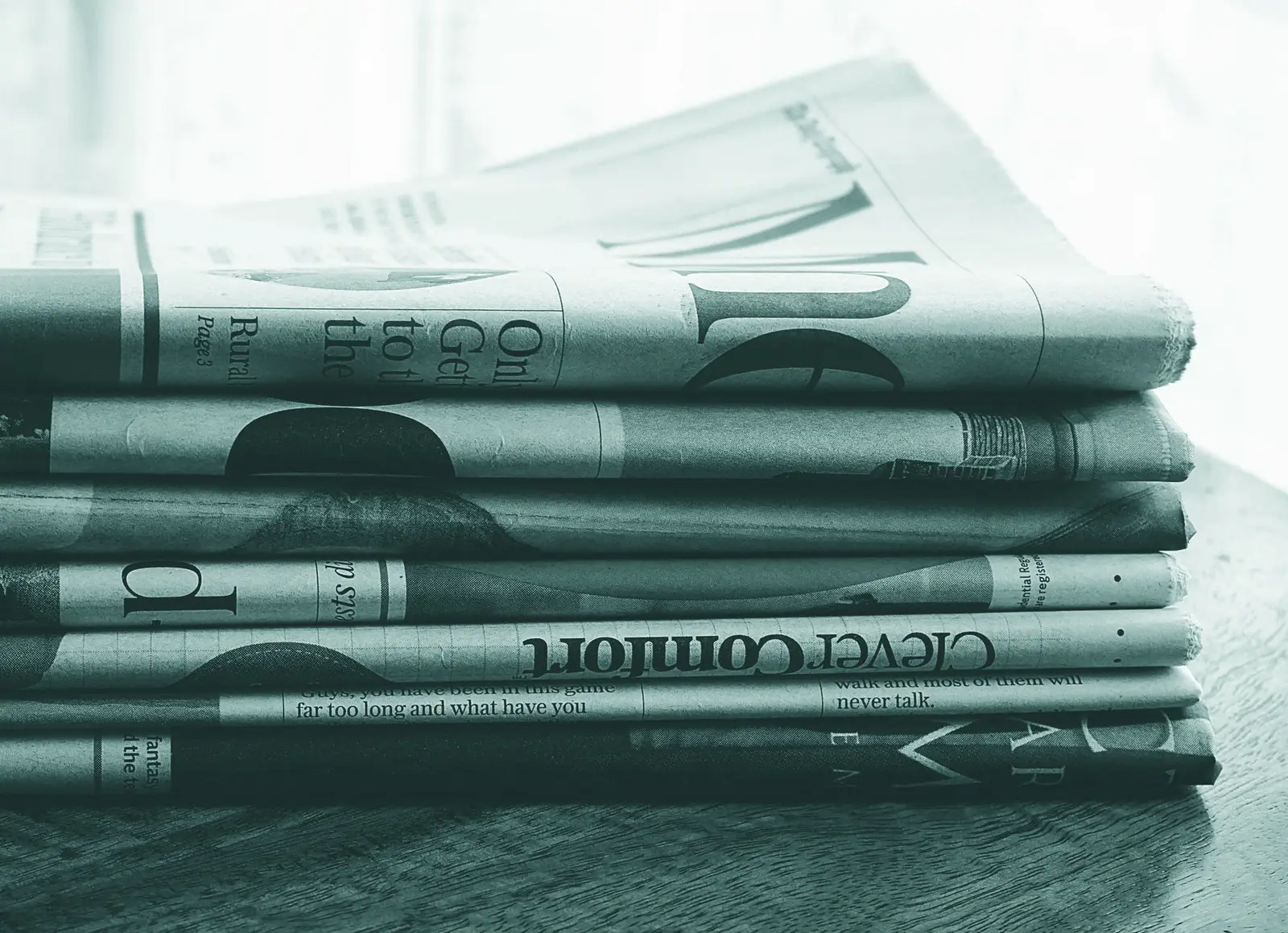A stack of folded newspapers placed on a wooden table, symbolizing news and information.